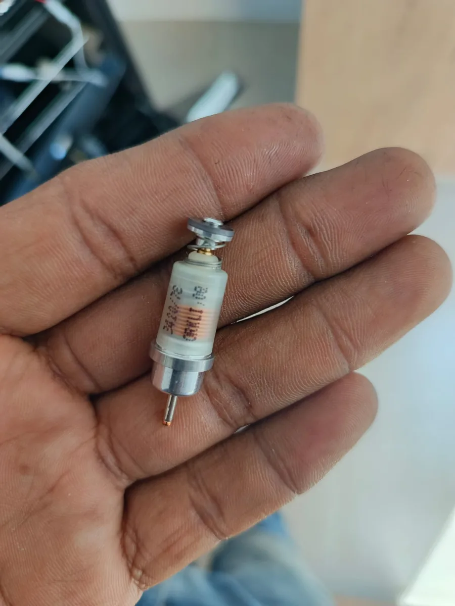 Mano sosteniendo una pieza cilíndrica pequeña con un pin metálico en un extremo